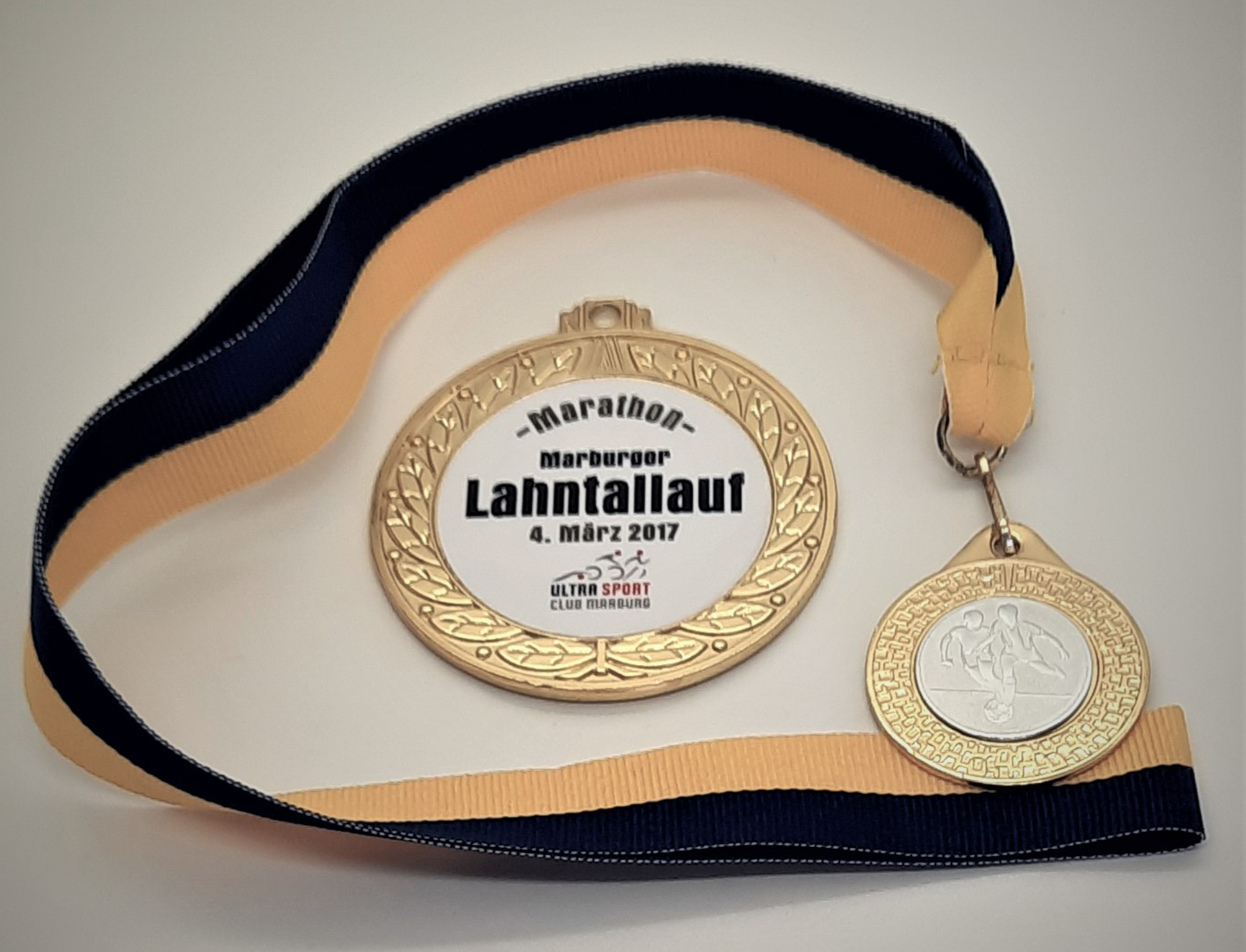 Medaille in gold mit Vereinslogo in weiß und schwarz-goldenem Band